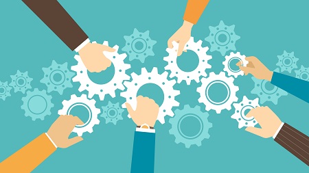 A flat-design conceptual vector illustration representing teamwork and collaboration on a teal background. Six distinct hands, each coming from a different sleeve color (brown, orange, teal, and striped), reach inward from the edges of the frame to hold and align an interconnected chain of white gears. Several faint, translucent gears float in the background to emphasize the mechanical theme. The hands work together to keep the central gear system moving in synchronization.
